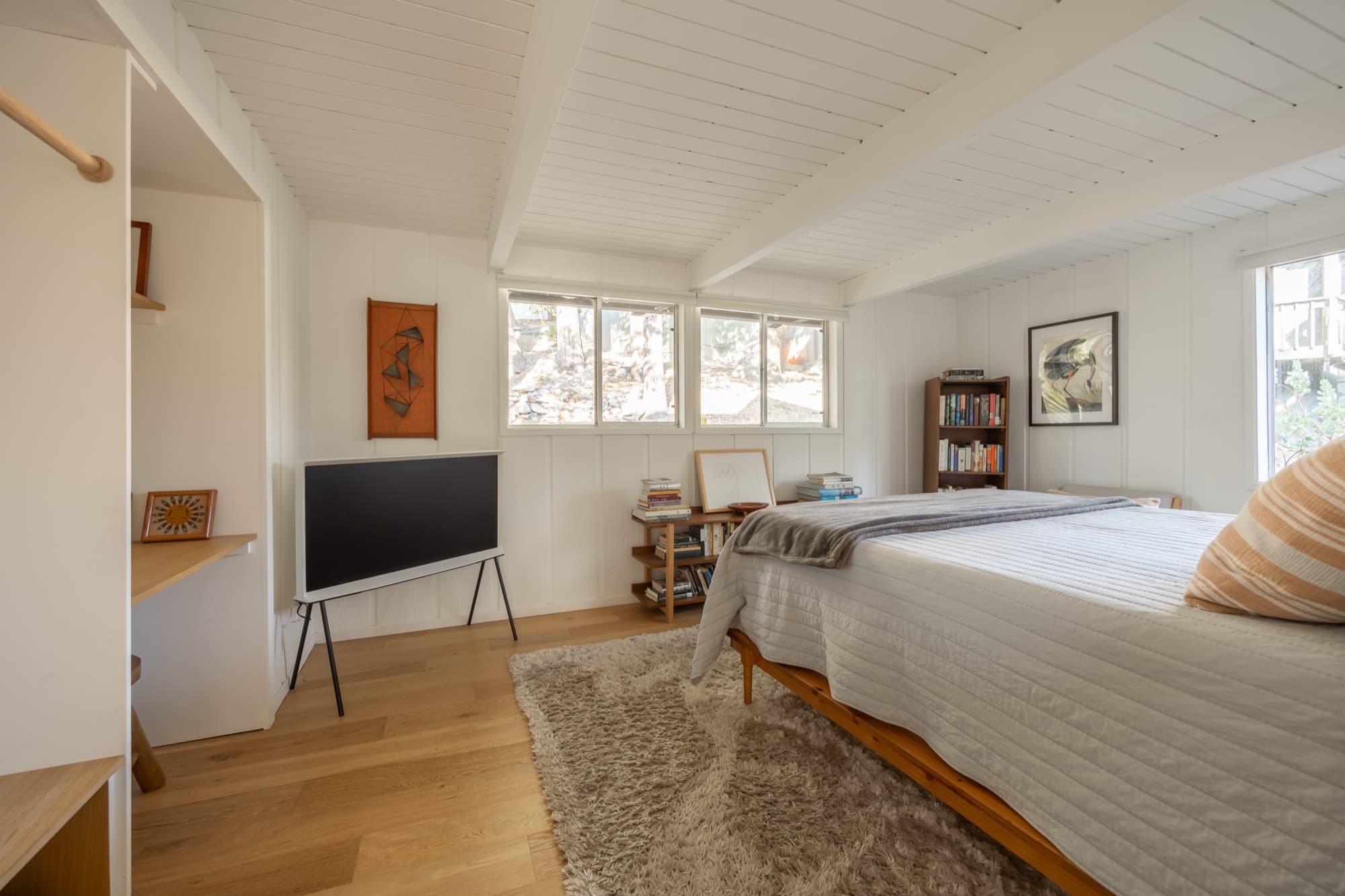 Primary bedroom with queen bed, hardwood floors, and Samsung Serif TV